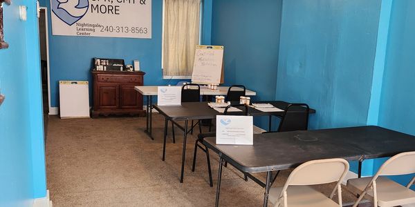 A small classroom with blue walls and tables for CPR and medical training.