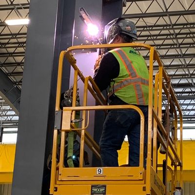 hydraulic lift with hydraulic tech career image. Tech is welding on hydraulic lift.