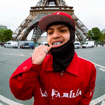 Person in red jacket and cap posing near the Eiffel Tower.