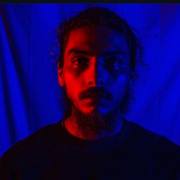 Portrait of a man with dramatic red and blue lighting.