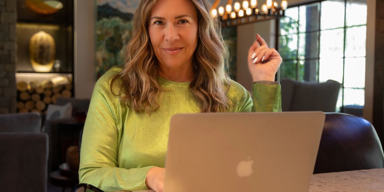 Woman in green top using a MacBook indoors.
