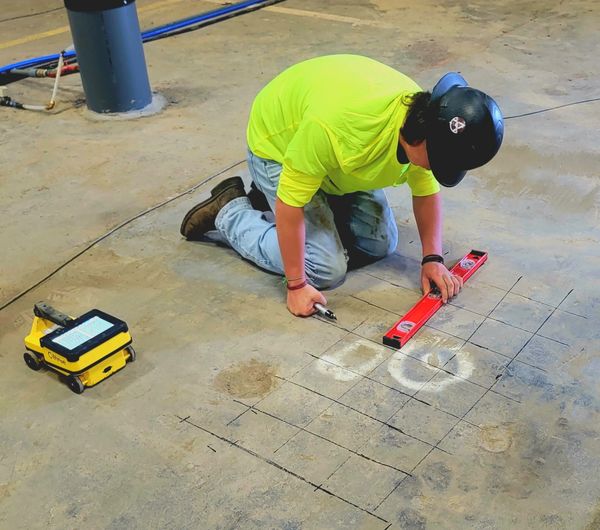 Worker marking floor with lines using a level.
