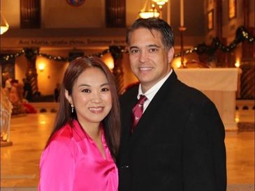A couple dressed elegantly and smiling indoors.