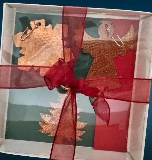 Metal ornaments in a gift box tied with a red ribbon.