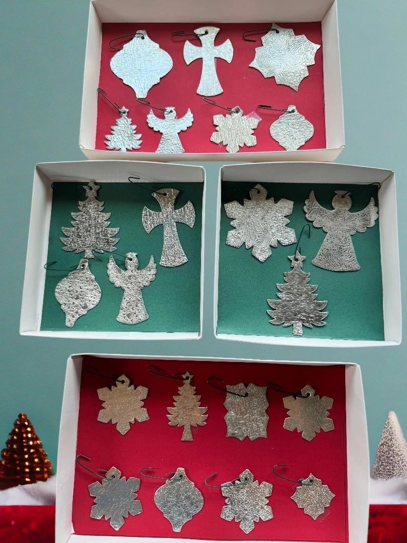 Silver Christmas ornaments in boxes with green and red backgrounds.