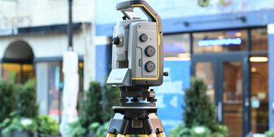 A surveying instrument set up outdoors in an urban area.