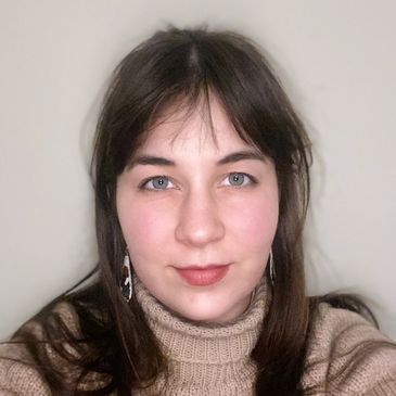 Young woman with blue eyes wearing a beige turtleneck sweater.