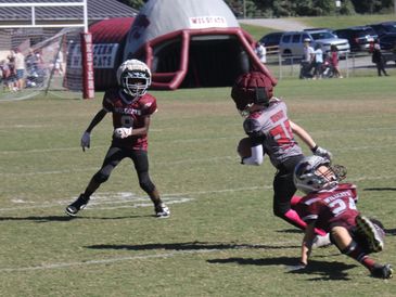 Kids playing tackle football on a field.