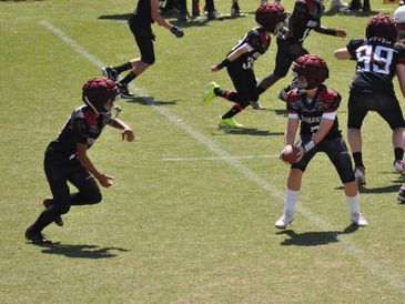 Kids playing football on a sunny field.