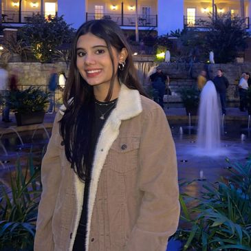 Young woman smiling near a lit fountain at night.