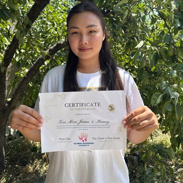 Young woman proudly holds a partnership certificate outdoors.