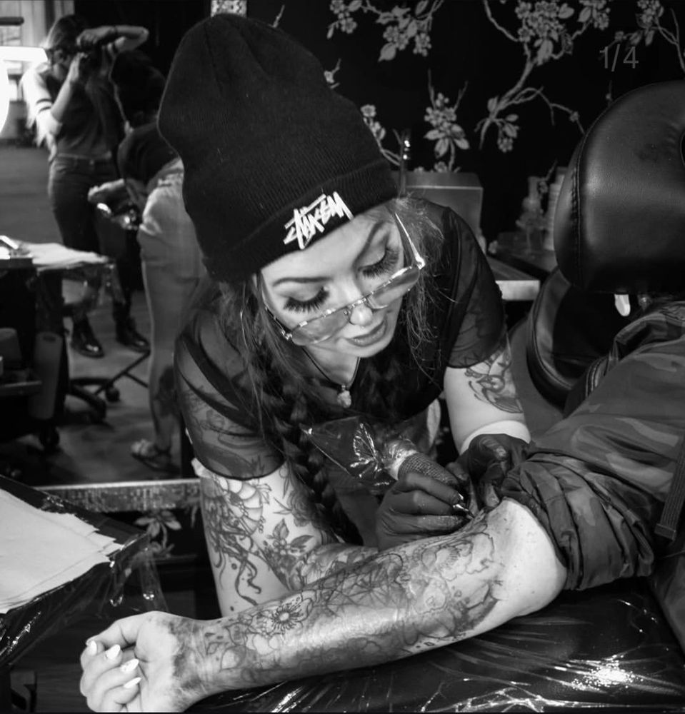 Tattoo artist working on a client's arm tattoo.
