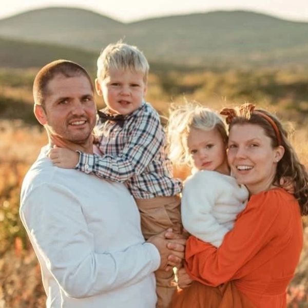 Family of four smiling outdoors.