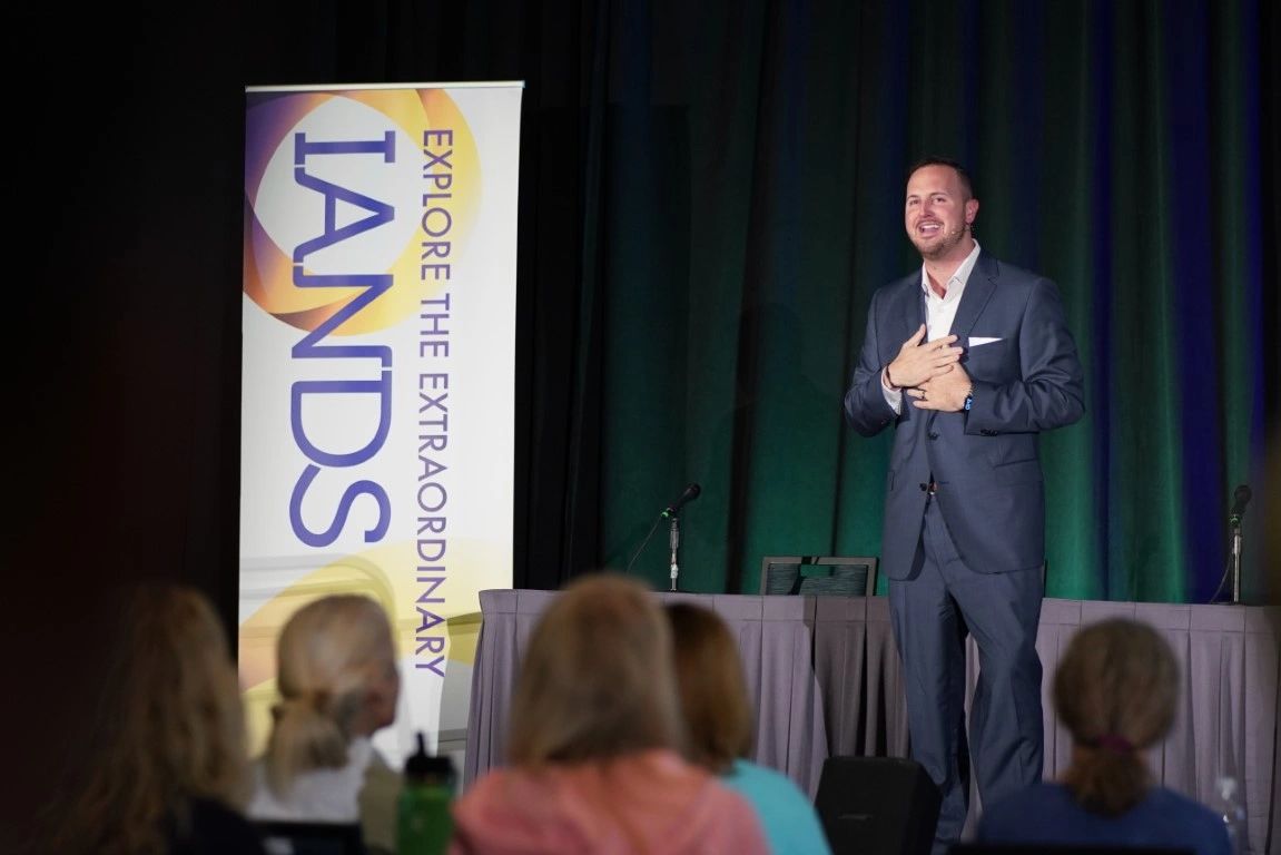 Chase Skylar DeMayo speaking onstage at an IANDS conference.