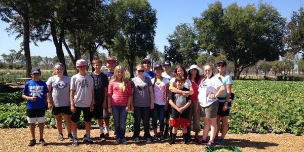 Group of kids and adults posing in a garden under sunlight.