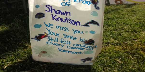 A handwritten note expressing missing Shawn Knutson, placed on grass.