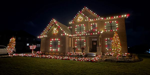 House beautifully decorated with red and white Christmas lights at night.