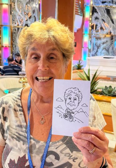 Woman holding a caricature drawing of herself riding a bike.