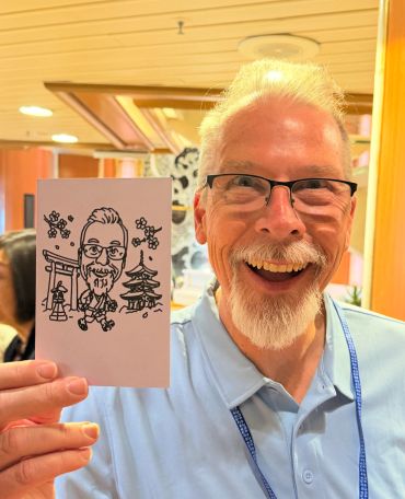 Man holding caricature drawing resembling himself.