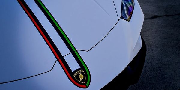 Front view of a white Lamborghini with racing stripes.