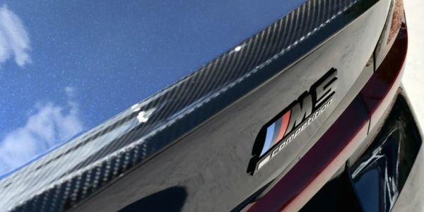 Close-up of a black car with an M Competition badge and carbon spoiler.