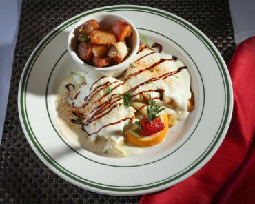 Dish with creamy sauce, roasted potatoes, and garnish.