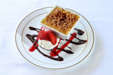 Crème brûlée dessert with strawberries and whipped cream.