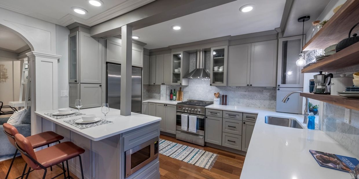 Gray Kitchen Shaker Cabinets and black hardware, stainless faucet and gas range oven, hardwood floor