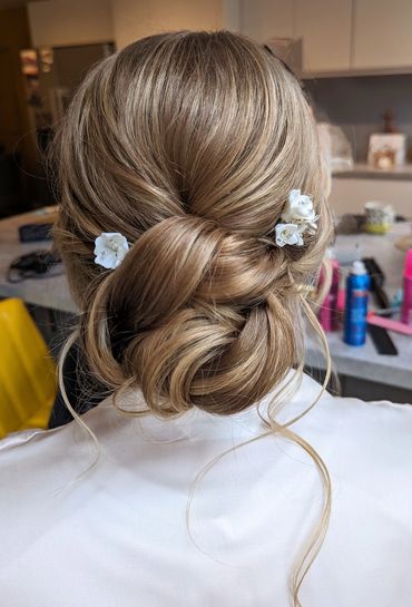 Elegant low bun hairstyle adorned with white flowers.