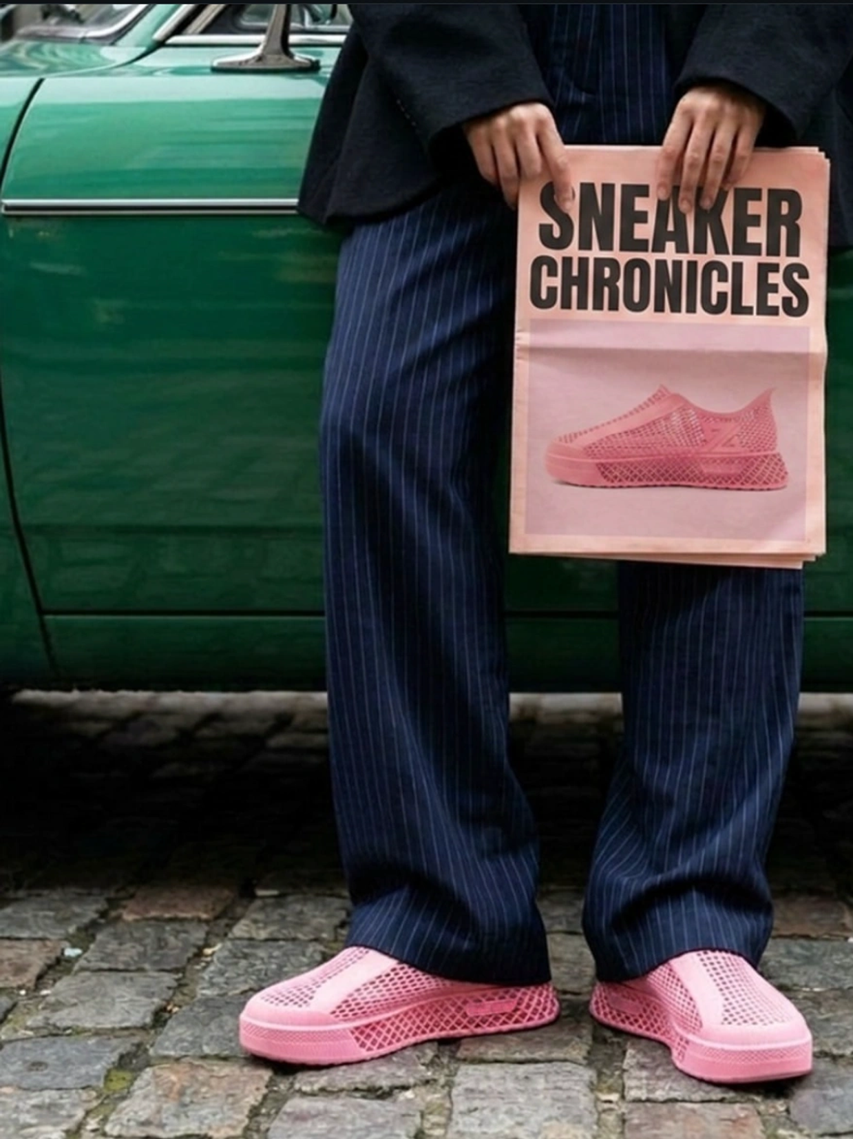 Person holding a "Sneaker Chronicles" magazine, wearing pink shoes.