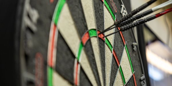 Three darts hitting the bullseye on a dartboard.