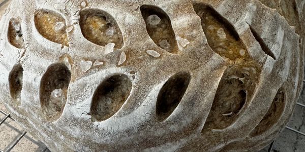Close-up of artisan bread with intricate scoring and rustic crust.