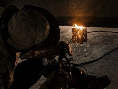 Welder working with sparks flying in dim light.