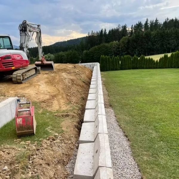 Construction site with retaining wall and excavator.