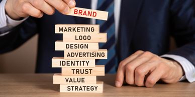 Businessman stacking blocks labeled with branding and marketing terms.