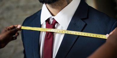 A man in a suit is being measured for tailoring.