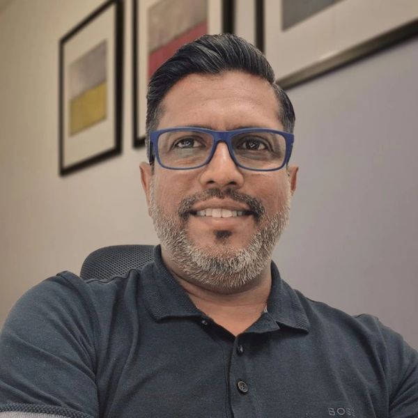 Man with glasses smiling while sitting indoors.