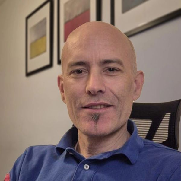 Smiling bald man with a goatee sitting in an office chair.
