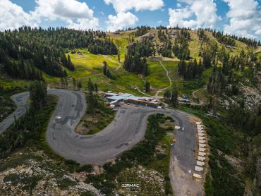 A winding mountain road with green hills and scattered trees.