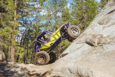 Yellow off-road vehicle climbing steep rock.