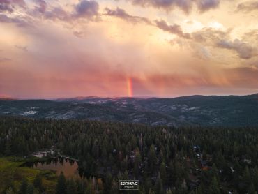 Rainbow over forested hills at sunset.