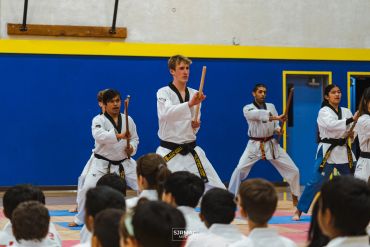 Martial artists practicing nunchaku in a gym.