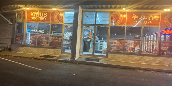 A grocery store at night with an illuminated 'OPEN' sign.