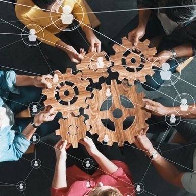People collaboratively holding wooden gears symbolizing teamwork and connectivity.