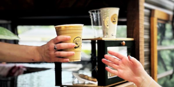Handing over an iced coffee outdoors.