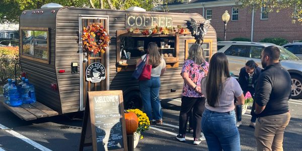 People queuing at a coffee food truck decorated for autumn.