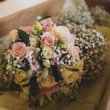 A delicate bouquet of pastel roses and white baby's breath flowers.