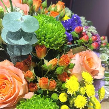 A vibrant bouquet featuring roses, green chrysanthemums, and yellow daisies.