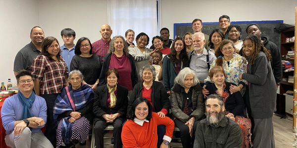 A diverse group of people posing together indoors, smiling warmly.
