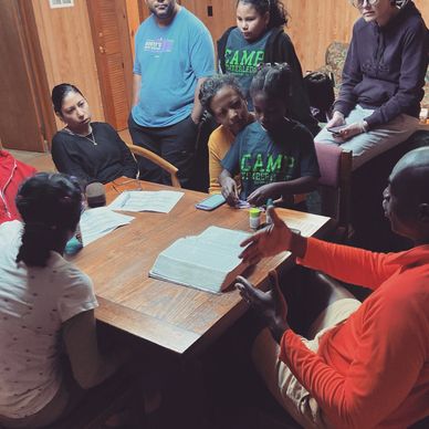 Group of people gathered around a table engaged in discussion or study.